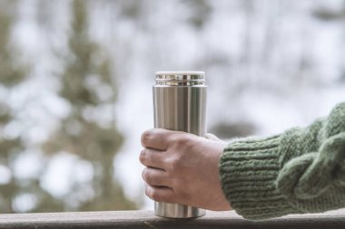 Sıcak bir içecekle termos tutan bir adam. Onda bir fincan kahve