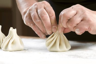 Aşçı ahşap masada khinkali yapıyor. İşlem hazırlığı Gürcistan yemeği. yiyecek konsepti.
