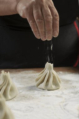 Aşçı ahşap masada khinkali yapıyor. İşlem hazırlığı Gürcistan yemeği. yiyecek konsepti.