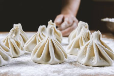 Aşçı ahşap masada khinkali yapıyor. İşlem hazırlığı Gürcistan yemeği. yiyecek konsepti.