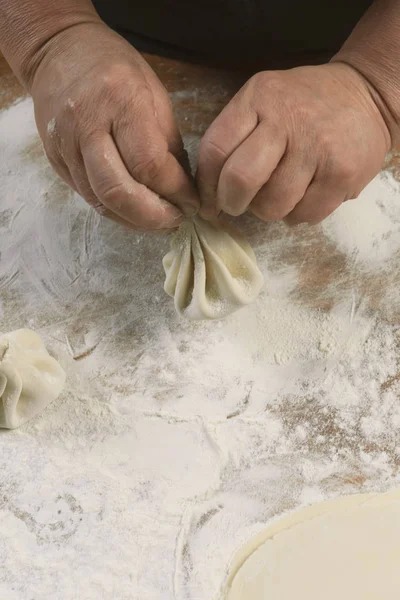 Aşçı ahşap masada khinkali yapıyor. İşlem hazırlığı Gürcistan yemeği. yiyecek konsepti.