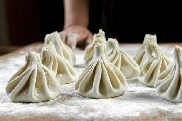 Aşçı ahşap masada khinkali yapıyor. İşlem hazırlığı Gürcistan yemeği. yiyecek konsepti.