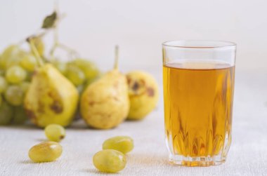 Beyaz ahşap arka planda bir bardak armut ve üzüm suyu.