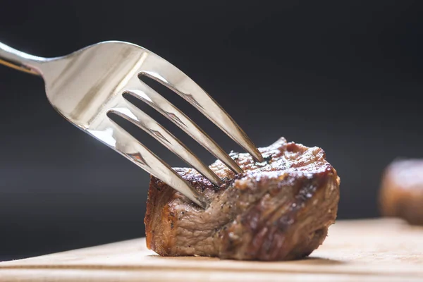 piece of meat on a fork, dark background