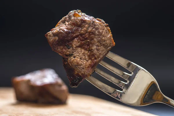 piece of meat on a fork, dark background