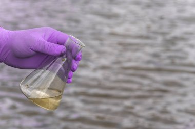 Analiz için nehirden örnek su. Bir test tüpü tutan eldiven. Ekoloji konsepti.