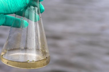 Analiz için nehirden örnek su. Bir test tüpü tutan eldiven. Ekoloji konsepti.