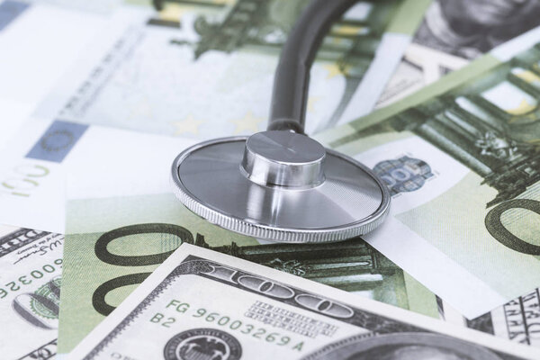 medical stethoscope on dollars and euro banknotes