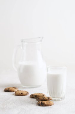 Çukulata parçalı kurabiye ve sütle beyaz ahşap arka planda bir bardak.