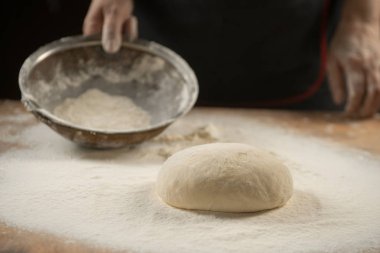 Hamur yoğurma fırını. Aşçı ahşap masada turta pişirmek için hamur yapıyor. İşlem hazırlığı ev yapımı hamur işi. Makarna, ekmek, spagetti, khachapuri, yemek konsepti.