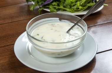 Yoğurt çorbası, ahşap masadaki bir tabakta otlar. Spa.