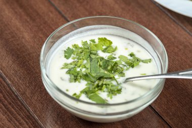 Yoğurt çorbası, ahşap masadaki bir tabakta otlar. Spa.