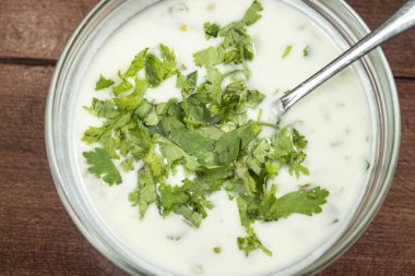 Yoğurt çorbası, ahşap masadaki bir tabakta otlar. Spa.