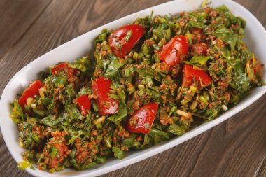 Bulgur, domates, maydanoz ve ahşap masadaki yeşil soğanlı Tabbouleh salatası. Geleneksel Ortadoğu ya da Arap yemeği.