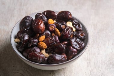 Beyaz ahşap arka planda fındık ve hurma karışımı sağlıklı yiyecekler.