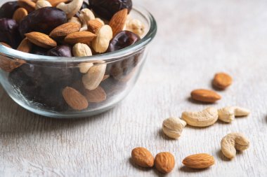 Beyaz ahşap arka planda fındık ve hurma karışımı sağlıklı yiyecekler.