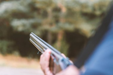 Erkek avcı av tüfeğiyle avlanmaya hazır. Avcı tüfeğini tutuyor..