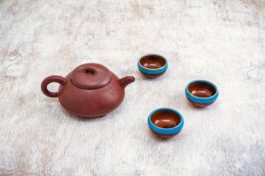 Kahverengi kil çaydanlık ve hafif ahşap zemin üzerinde fincanlar