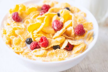 Bir kase mısır gevreği, sütlü, taze ahududu, yabanmersini. Sağlıklı kahvaltı için, kapatın.