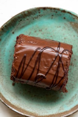 Beyaz ahşap arka planda seramik tabakta çikolatalı kek, yakın plan. Sarhoş vişneli kek.