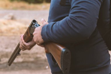 Erkek avcı av tüfeğiyle avlanmaya hazır. Avcı tüfeği tutuyor. Avcı tüfeğe saldırıyor.