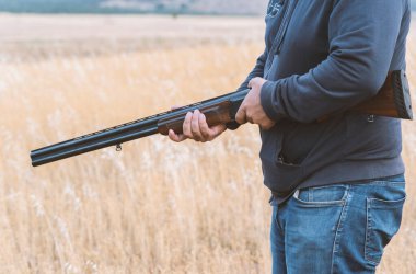 Erkek avcı av tüfeğiyle avlanmaya hazır. Avcı tüfeğini tutuyor..