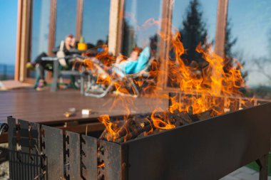 Portatif bir barbekü merkezinde küçük odun parçaları üzerinde yanan odun kütükleri ile taze yakılmış barbekü ateşi.