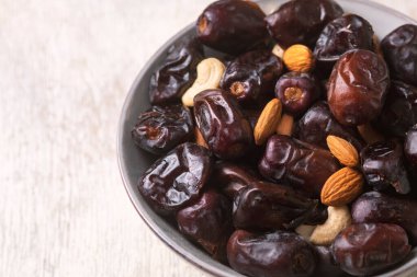 Beyaz ahşap arka planda fındık ve hurma karışımı sağlıklı yiyecekler.