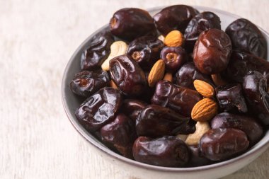 Beyaz ahşap arka planda fındık ve hurma karışımı sağlıklı yiyecekler.