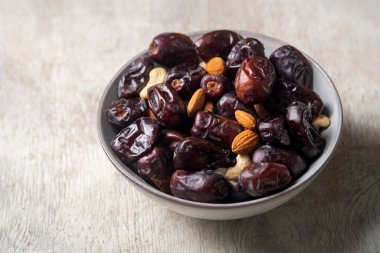 Beyaz ahşap arka planda fındık ve hurma karışımı sağlıklı yiyecekler.