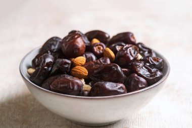 Beyaz ahşap arka planda fındık ve hurma karışımı sağlıklı yiyecekler.