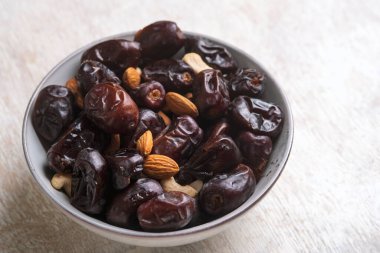 Beyaz ahşap arka planda fındık ve hurma karışımı sağlıklı yiyecekler.