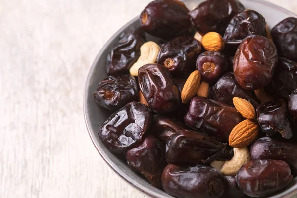 Beyaz ahşap arka planda fındık ve hurma karışımı sağlıklı yiyecekler.