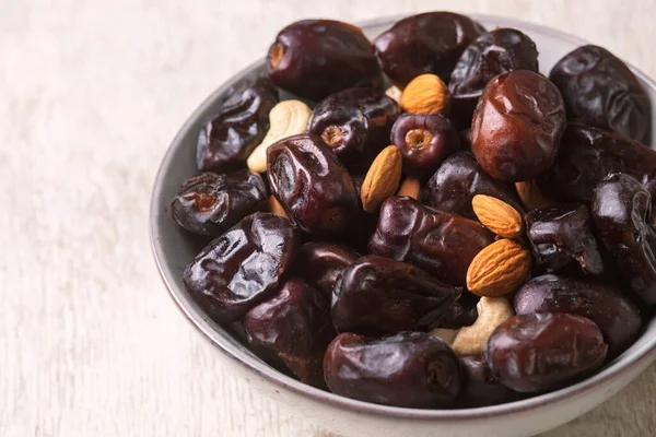Beyaz ahşap arka planda fındık ve hurma karışımı sağlıklı yiyecekler.