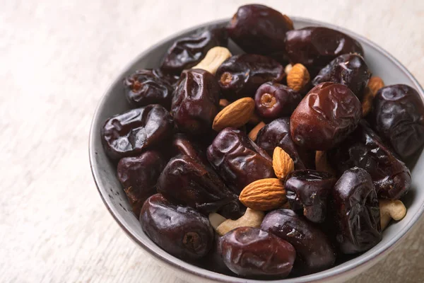 Beyaz ahşap arka planda fındık ve hurma karışımı sağlıklı yiyecekler.