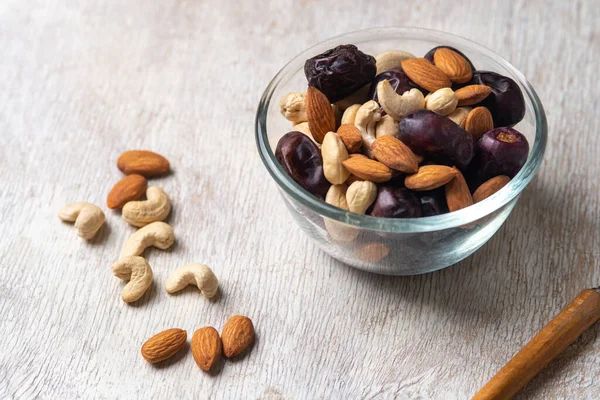 Beyaz ahşap arka planda fındık ve hurma karışımı sağlıklı yiyecekler.