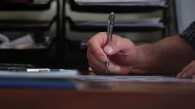 An adult man writes with a pen. Hands are stained with ink.  Slow motion