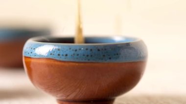Person pouring tea from a Chinese teapot in a cup , tea spills on the table