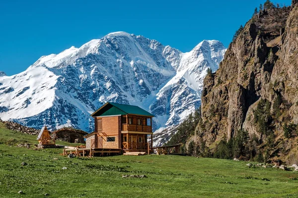 House in the mountains. Elbrus region. In the background, the glacier in the form of the number seven.