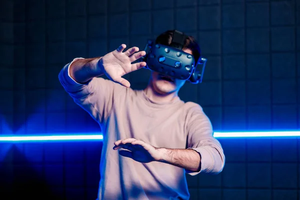 Молодой парень играет в видеоигры в игровой комнате в шлеме виртуальной реальности. Игровой клуб . — стоковое фото