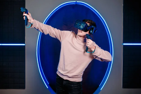 A young guy plays video games in a game room in a virtual reality helmet. gaming club.