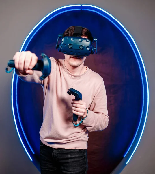 A young guy plays video games in a game room in a virtual reality helmet. gaming club.