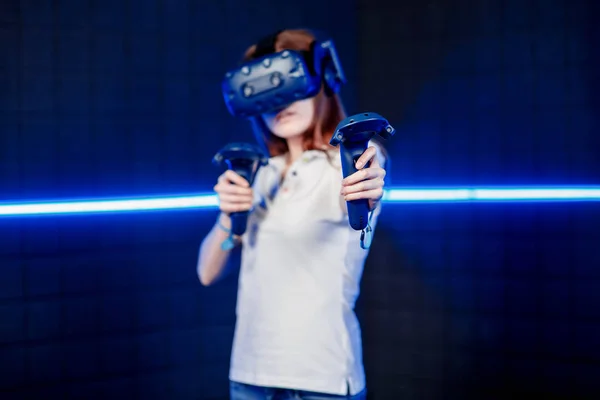 Uma jovem em um capacete de realidade virtual na sala de jogos está jogando um jogo de vídeo . — Fotografia de Stock