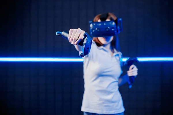 Uma jovem em um capacete de realidade virtual na sala de jogos está jogando um jogo de vídeo . — Fotografia de Stock