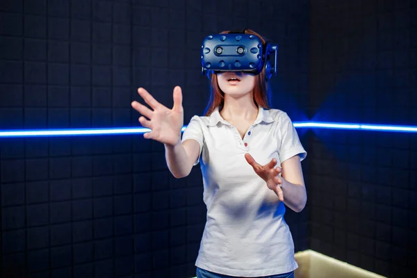 A young girl in a virtual reality helmet plays in a video game club.