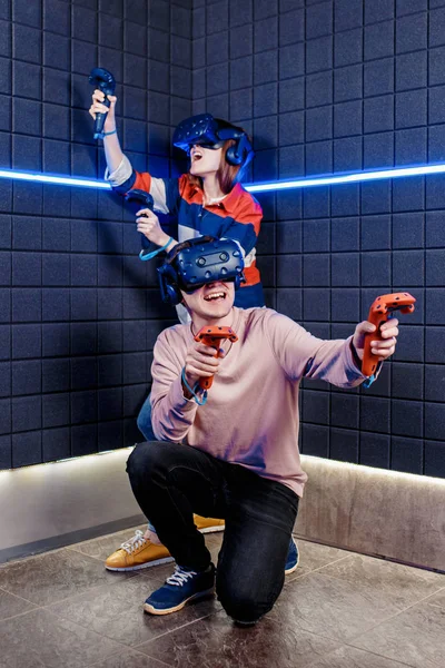 Young guy and girl in a virtual reality helmet playing video games in a club — Stock Photo, Image