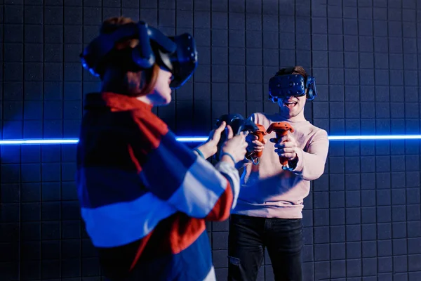 Young guy and girl in a virtual reality helmet playing video games in a club — Stock Photo, Image
