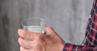 adam ilaç alır. hasta bir bardak su ile hapları alır, bir yüz olmadan