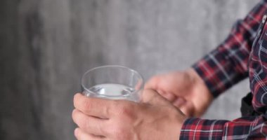 adam ilaç alır. hasta bir bardak su ile hapları alır, bir yüz olmadan