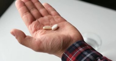 adam ilaç alır. hasta bir bardak su ile hapları alır, bir yüz olmadan